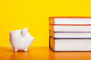 A piggy bank and a pile of books on a yellow background